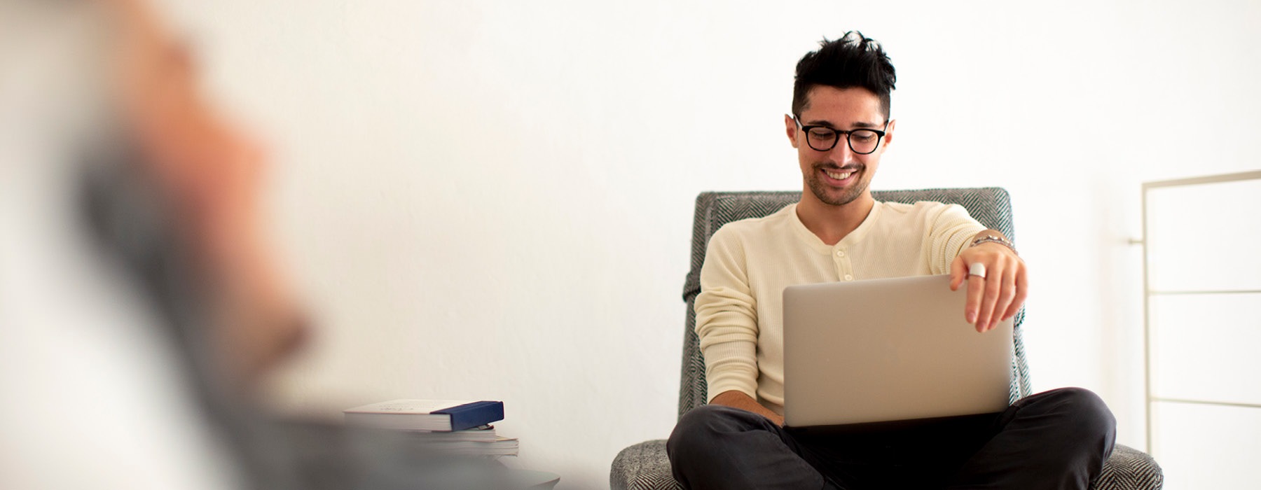 man sits on a chair looking at his laptop
